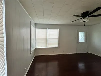 a view of an empty room with a window and wooden floor