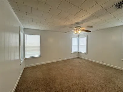 an empty room with a chandelier fan and windows