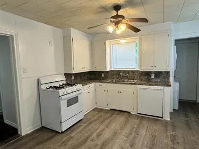 a kitchen with granite countertop white cabinets and white appliances