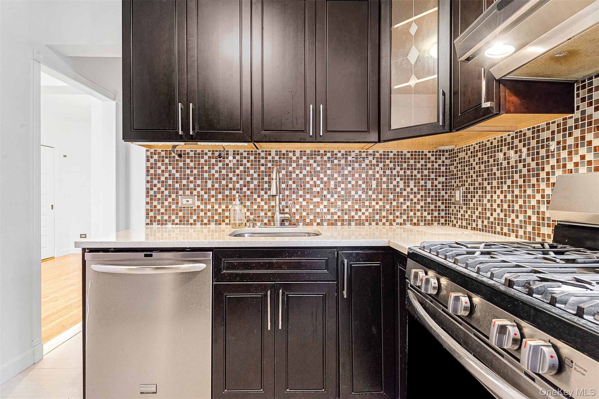 67-38 108th Street, Unit D47 Queens, NY 11375 - Photo 13 of 24 a kitchen with granite countertop a sink a stove and wooden cabinets