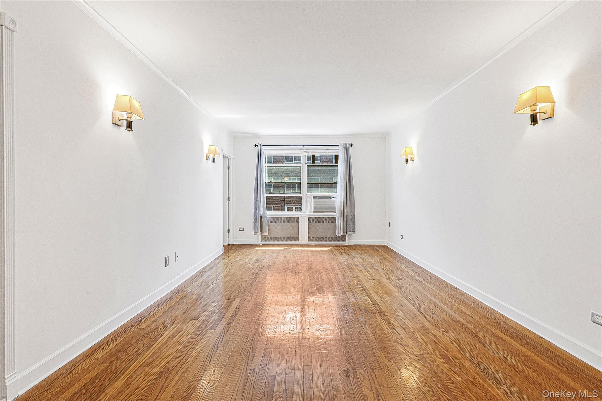 67-38 108th Street, Unit D47 Queens, NY 11375 - Photo 7 of 24 an empty room with wooden floor and windows