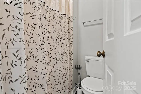 a white toilet sitting next to a shower curtain