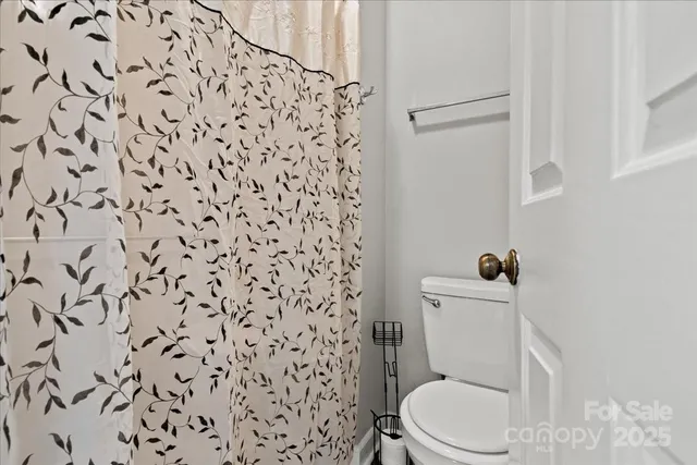 a white toilet sitting next to a shower curtain