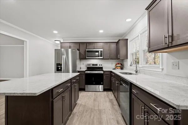 a kitchen with stainless steel appliances granite countertop a refrigerator a sink a stove a microwave and wooden cabinets