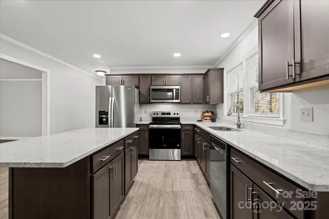 a kitchen with stainless steel appliances granite countertop a refrigerator a sink a stove a microwave and wooden cabinets