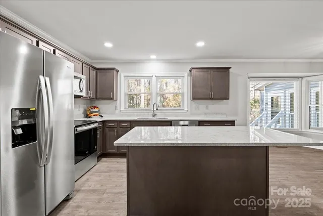 a large kitchen with granite countertop a sink stainless steel appliances and cabinets
