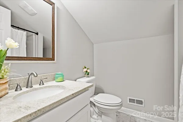 a bathroom with a granite countertop sink mirror vanity and toilet