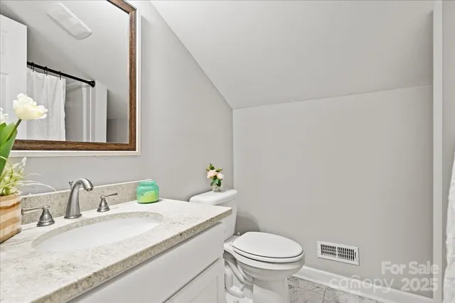 a bathroom with a granite countertop sink mirror vanity and toilet