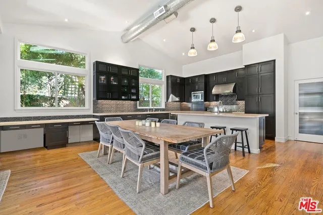 a dining table with kitchen view and a large window