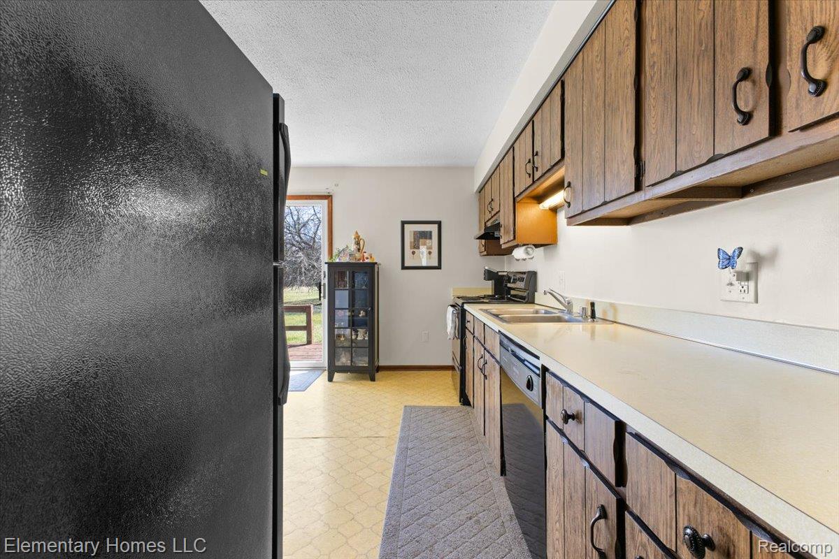 1650 Cove Road Goodells, MI 48027 - Photo 21 of 49 Kitchen with light floors, black appliances, light countertops, and a textured ceiling