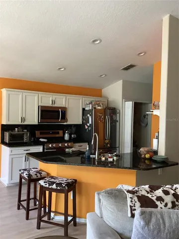 a living room with furniture a flat screen tv and kitchen view