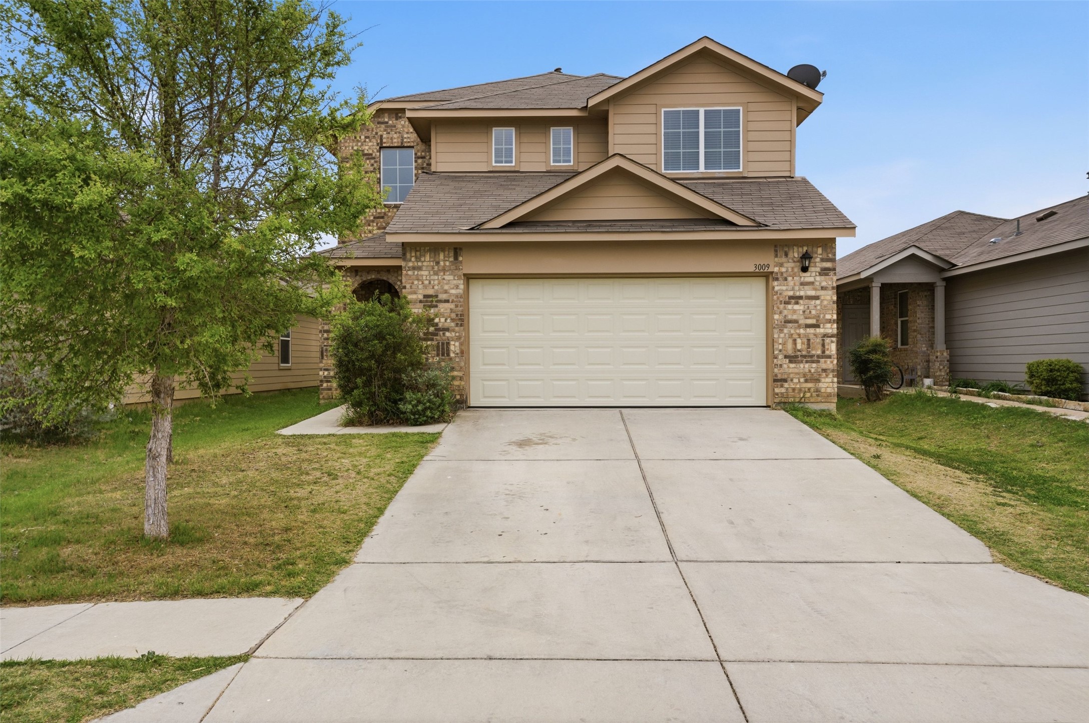 Traditional-style home with brick siding, driveway, a front lawn, and roof with shingles