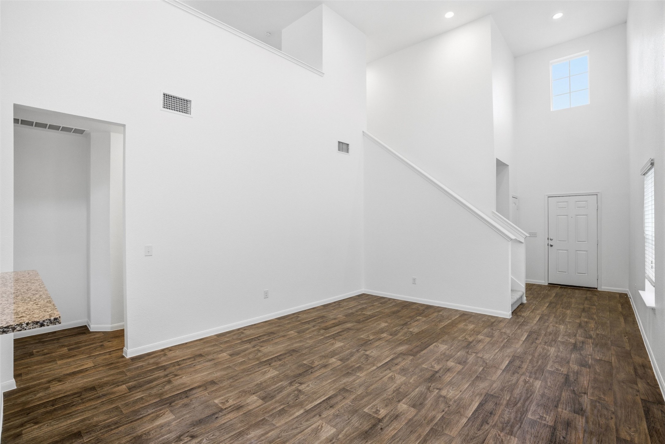 3009 Tilmon Ln. Austin, TX 78725 - Photo 12 of 33 Unfurnished living room featuring a high ceiling, dark wood-style floors, recessed lighting, and healthy amount of natural light