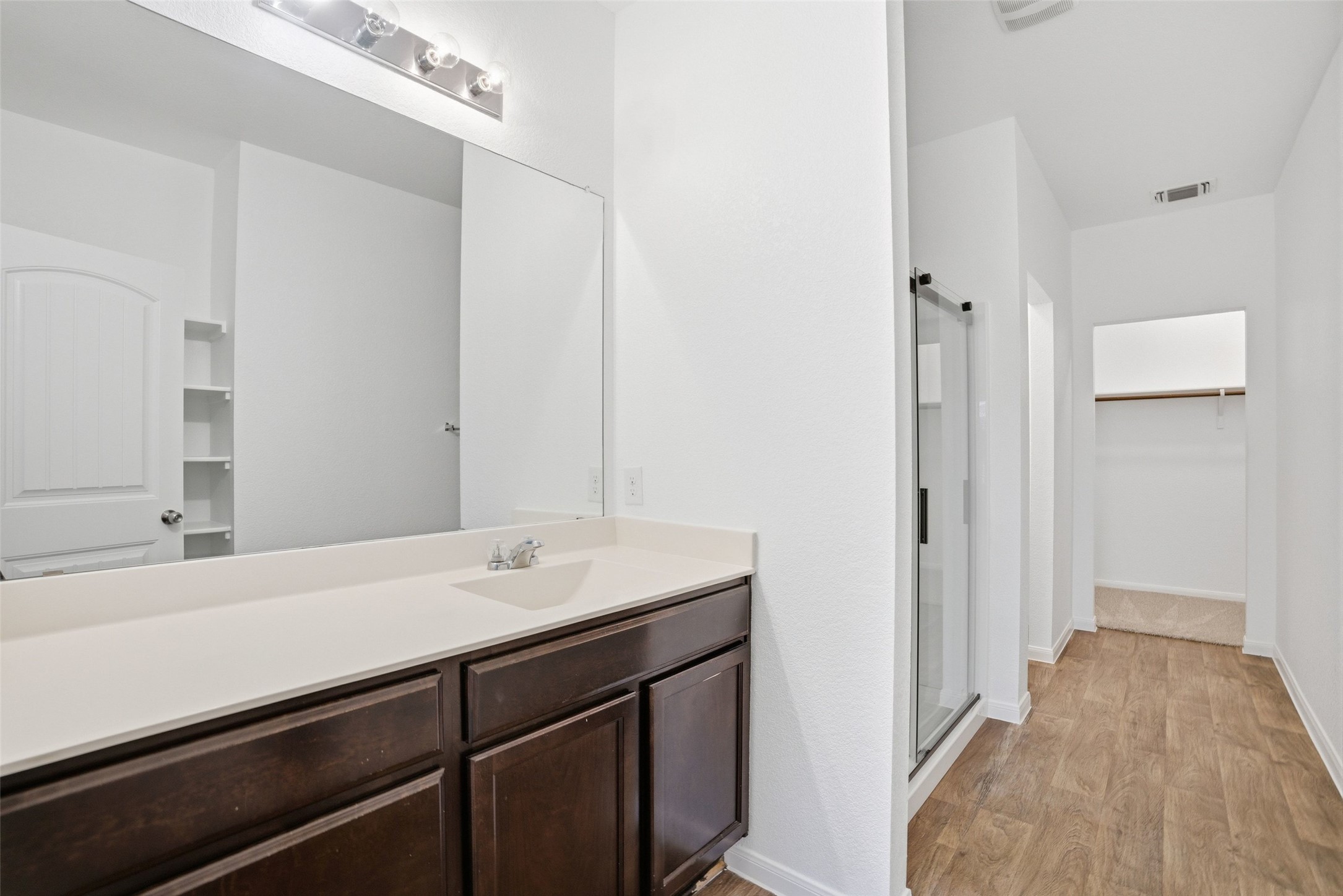 3009 Tilmon Ln. Austin, TX 78725 - Photo 13 of 33 Full bath featuring a walk in closet, a shower stall, vanity, and light wood-style flooring