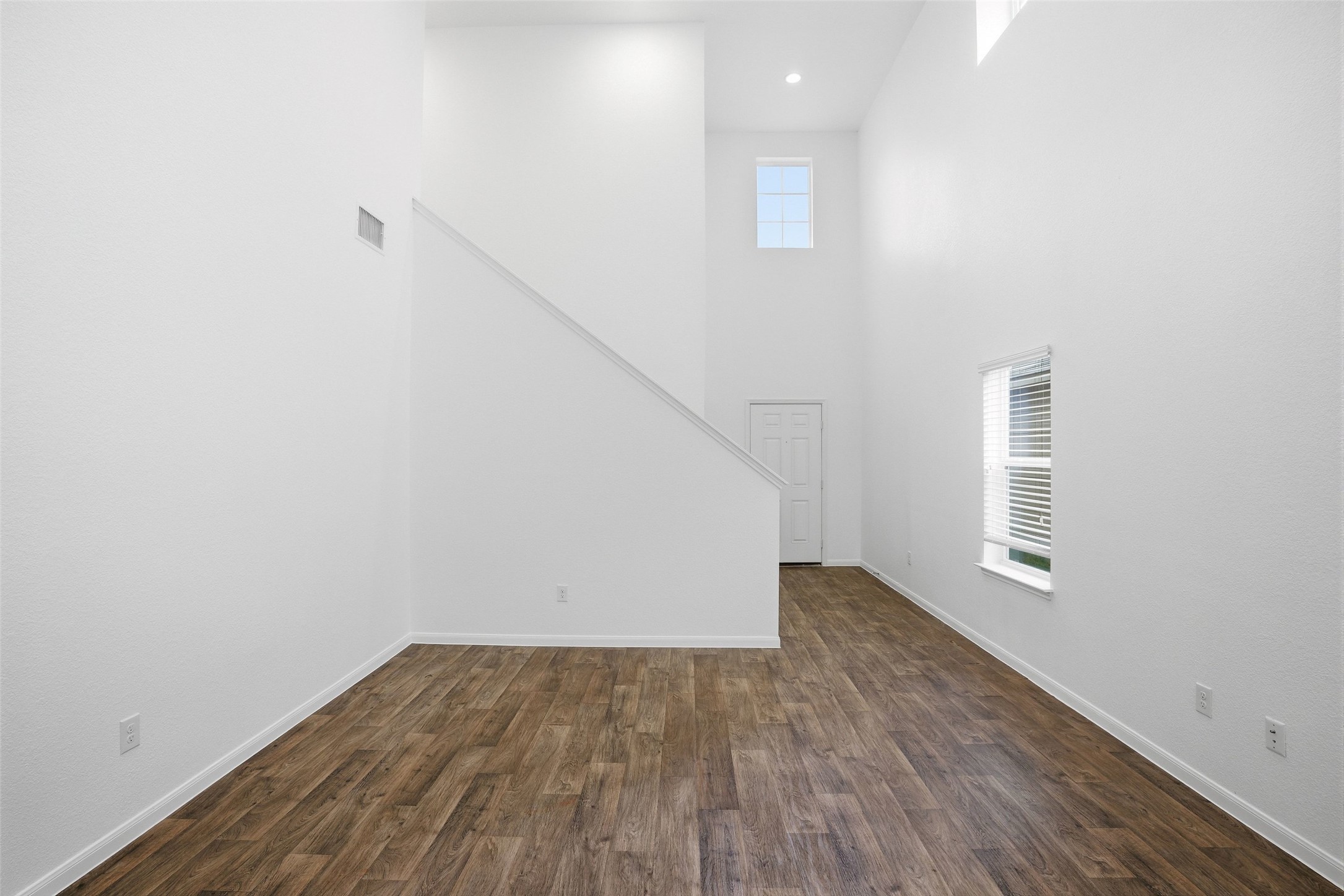 3009 Tilmon Ln. Austin, TX 78725 - Photo 10 of 33 Unfurnished living room with a high ceiling, dark wood-style floors, healthy amount of natural light, and recessed lighting