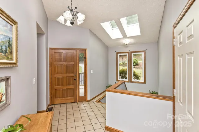 a living room with stainless steel appliances furniture a chandelier and a window