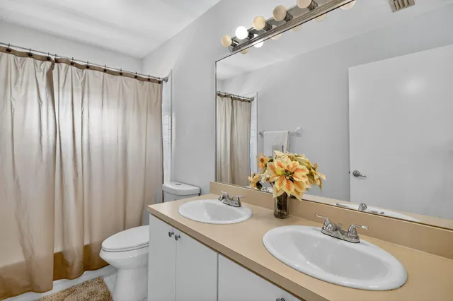 a bathroom with a granite countertop sink a toilet a mirror and shower