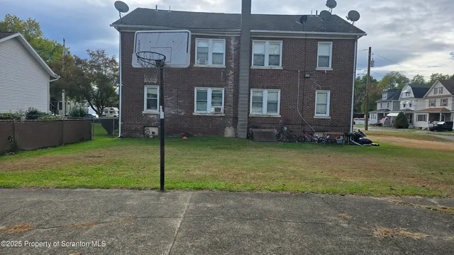 a view of a brick house with a yard and a large tree
