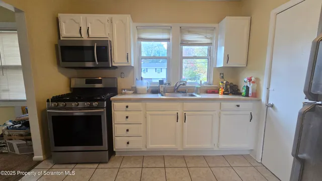 a kitchen with white cabinets and appliances