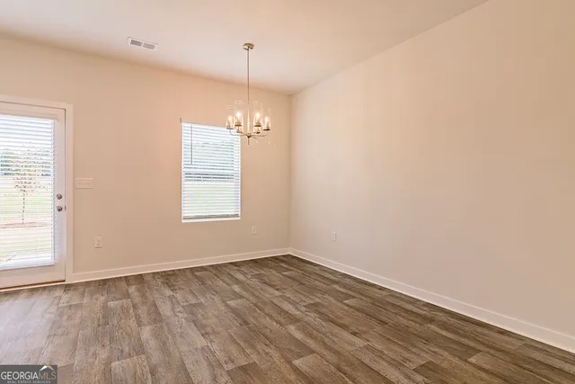 an empty room with wooden floor exposed radiator and windows
