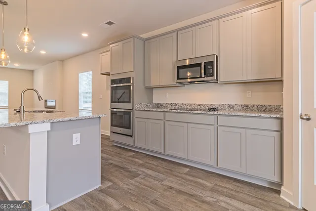 a kitchen with stainless steel appliances granite countertop a stove a sink and a microwave