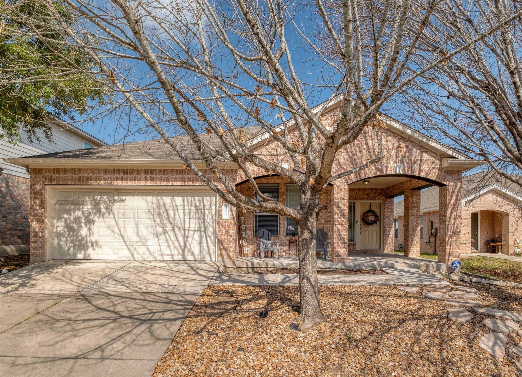 View of front facade with brick siding, an attached garage, concrete driveway, and covered porch