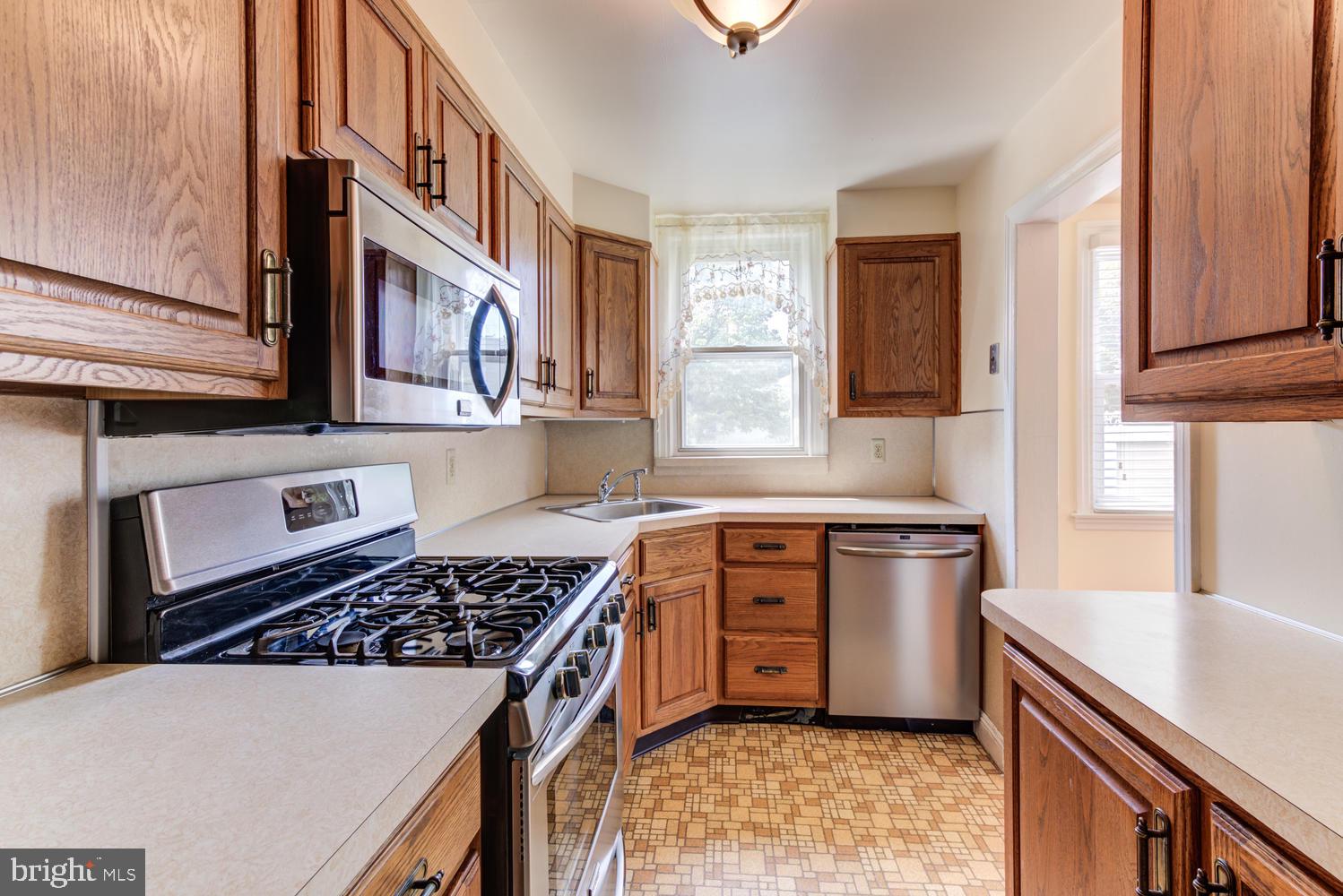 36 Woodbine Road Havertown, PA 19083 - Photo 10 of 34 a kitchen with stainless steel appliances a stove a sink cabinets and a window