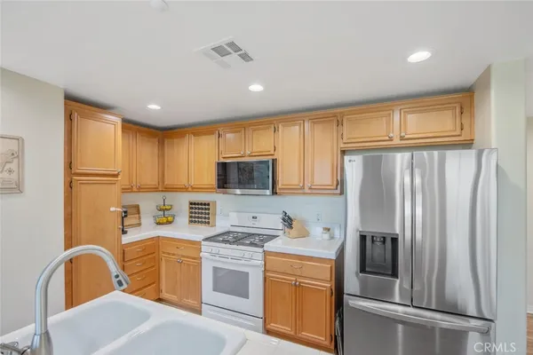 a kitchen with stainless steel appliances granite countertop a refrigerator a sink dishwasher a stove and white cabinets with wooden floor
