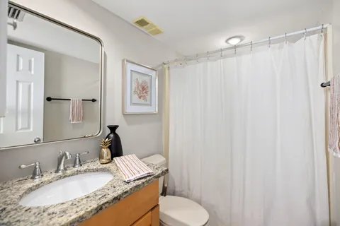 a bathroom with a granite countertop sink toilet and a mirror