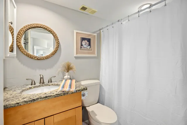 a bathroom with a granite countertop sink mirror vanity and toilet