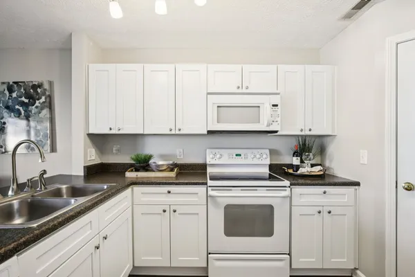 a kitchen with white cabinets and white appliances