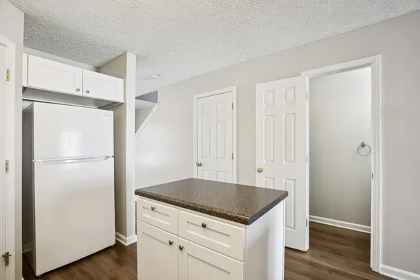 a kitchen with a sink dishwasher and white cabinets with wooden floor