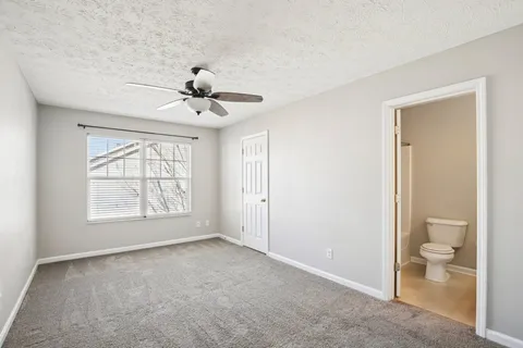 an empty room with a chandelier fan and windows