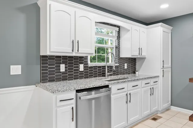 a kitchen with stainless steel appliances granite countertop a sink a stove and white cabinets