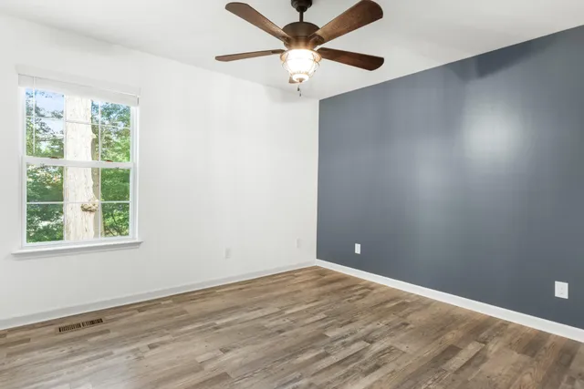 an empty room with a window and a fan