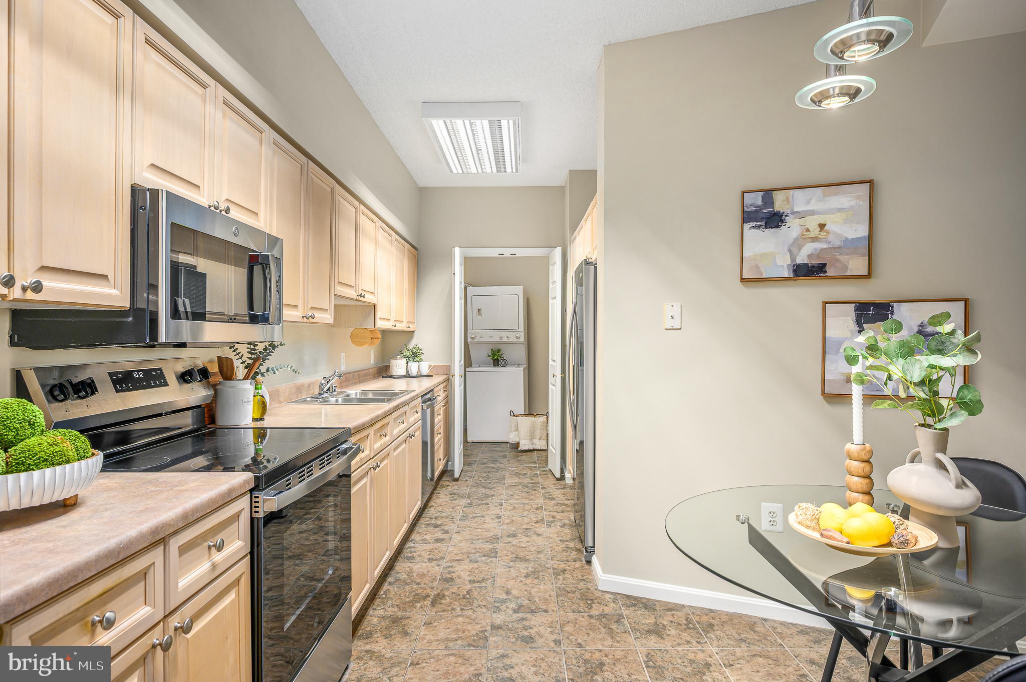 19375 Cypress Ridge Terrace, Unit 114 Leesburg, VA 20176 - Photo 16 of 42 a large kitchen with stainless steel appliances kitchen island granite countertop a table chairs in it and a window