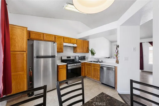 a kitchen with stainless steel appliances granite countertop a refrigerator a stove and a sink