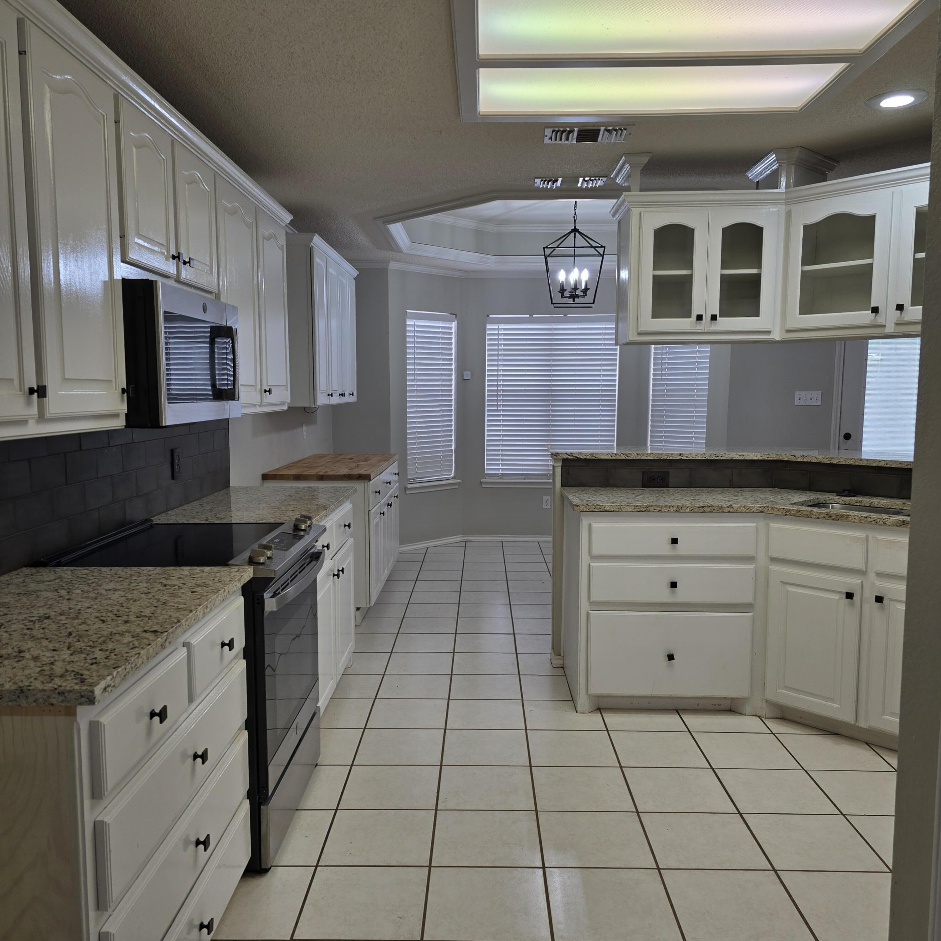 6701 Chicago Avenue Lubbock, TX 79424 - Photo 10 of 35 a kitchen with stainless steel appliances granite countertop a stove a sink and a microwave