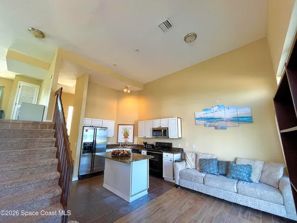 a living room with couches and a flat screen tv with kitchen view