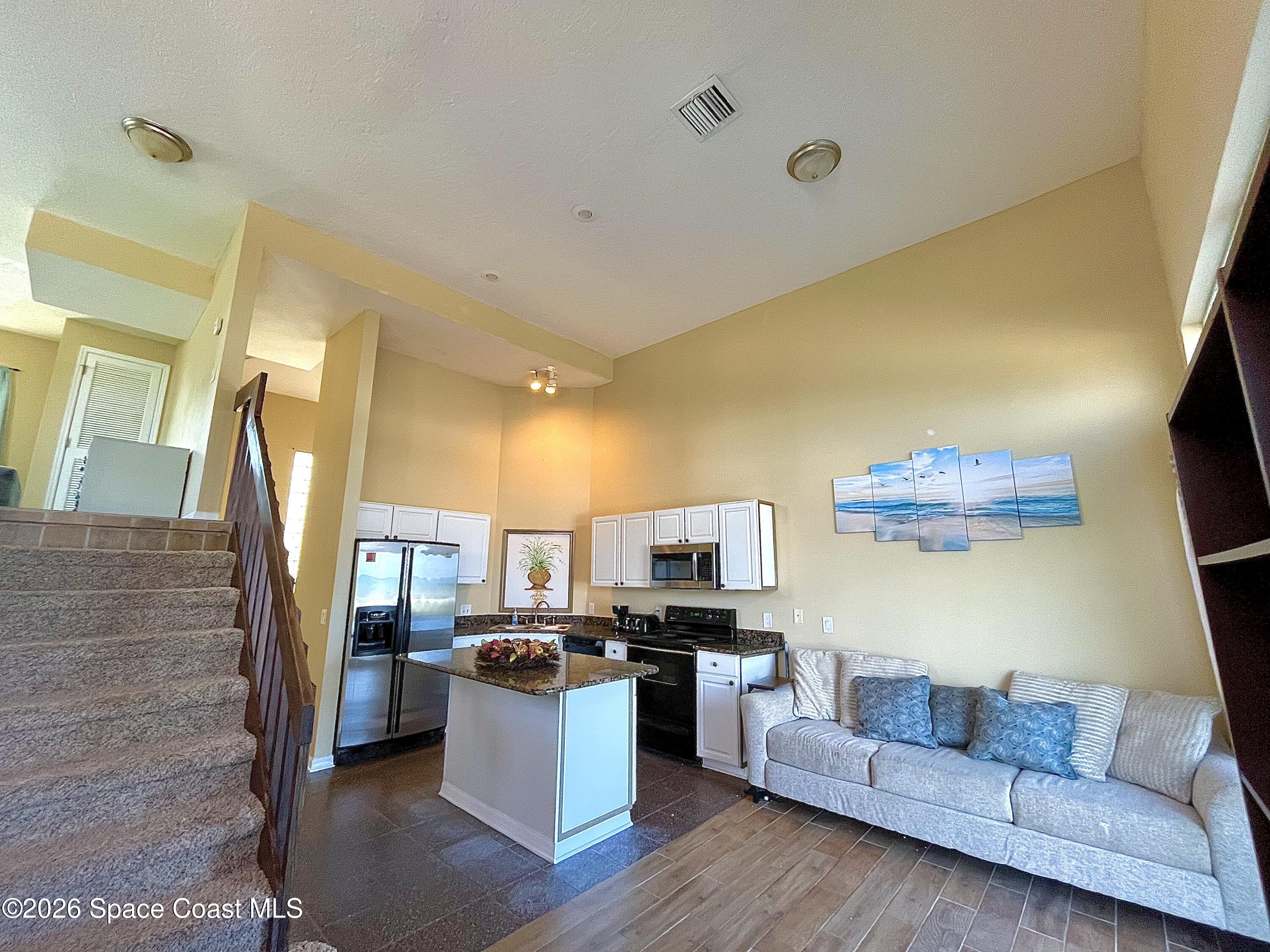 799 Shell Street Satellite Beach, FL 32937 - Photo 9 of 32 a living room with couches and a flat screen tv with kitchen view