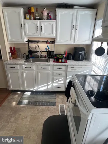a kitchen with white cabinets and sink