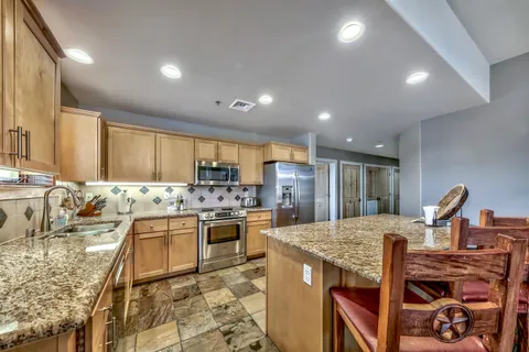 a open kitchen with stainless steel appliances granite countertop a sink stove and refrigerator