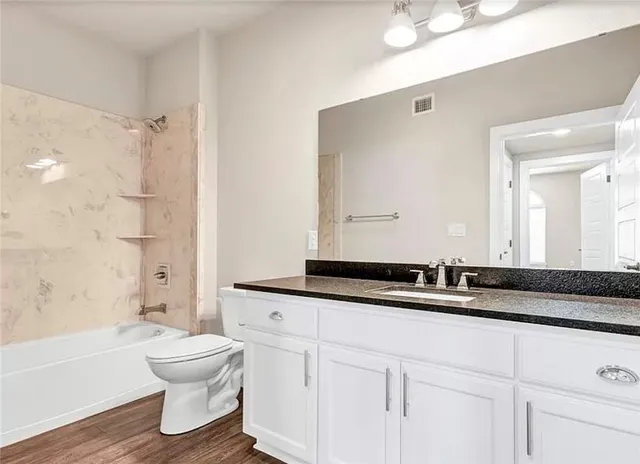 a bathroom with a granite countertop sink mirror toilet and bathtub