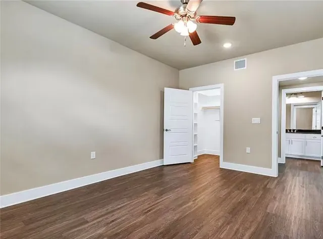 an empty room with wooden floor closet and windows