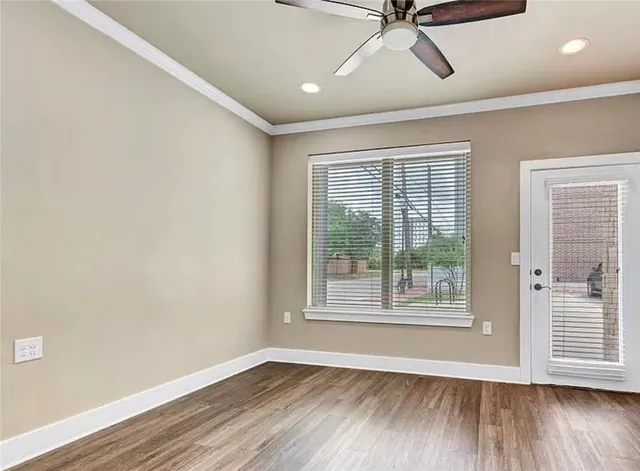 an empty room with wooden floor fan and windows
