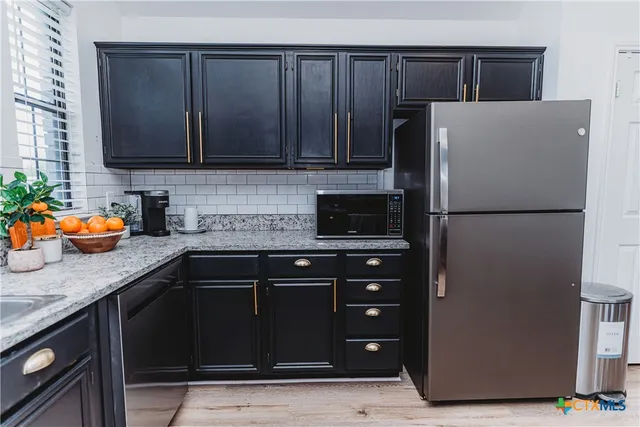 a kitchen with stainless steel appliances granite countertop a refrigerator and a sink