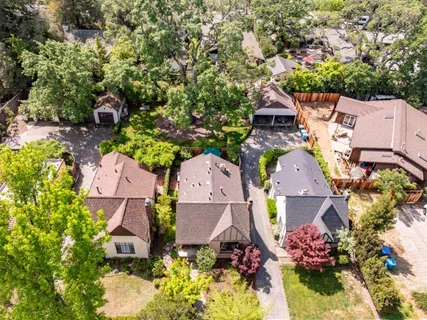 an aerial view of residential houses with outdoor space and trees all around