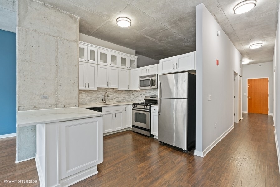 235 West Van Buren Street, Unit 1622 Chicago, IL 60607 - Photo 13 of 29 a kitchen with cabinets stainless steel appliances and wooden floor
