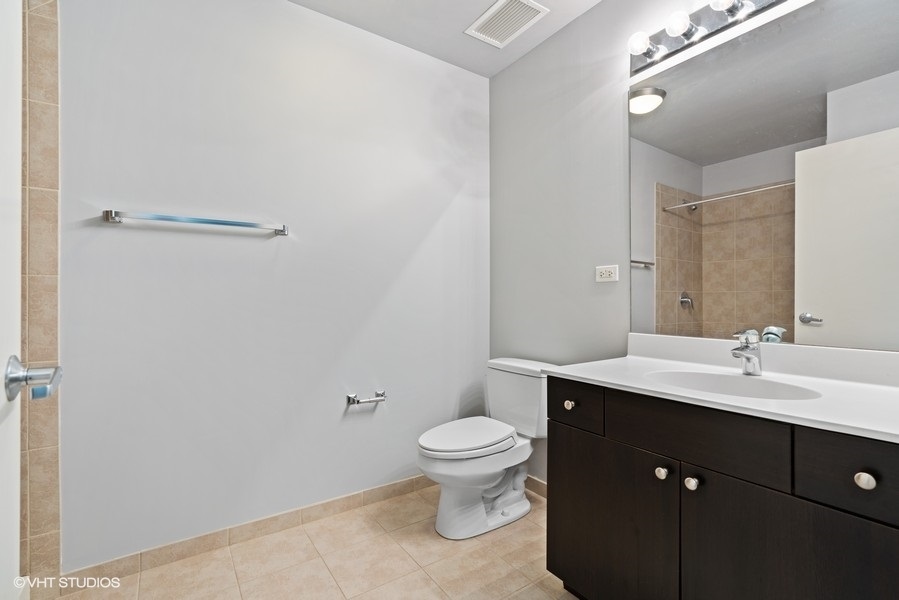 235 West Van Buren Street, Unit 1622 Chicago, IL 60607 - Photo 18 of 29 a bathroom with a granite countertop sink a toilet and a mirror