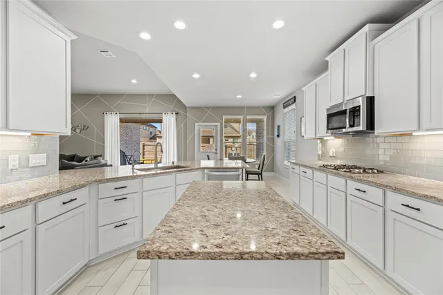 a large kitchen with kitchen island granite countertop a large counter top space appliances and cabinets